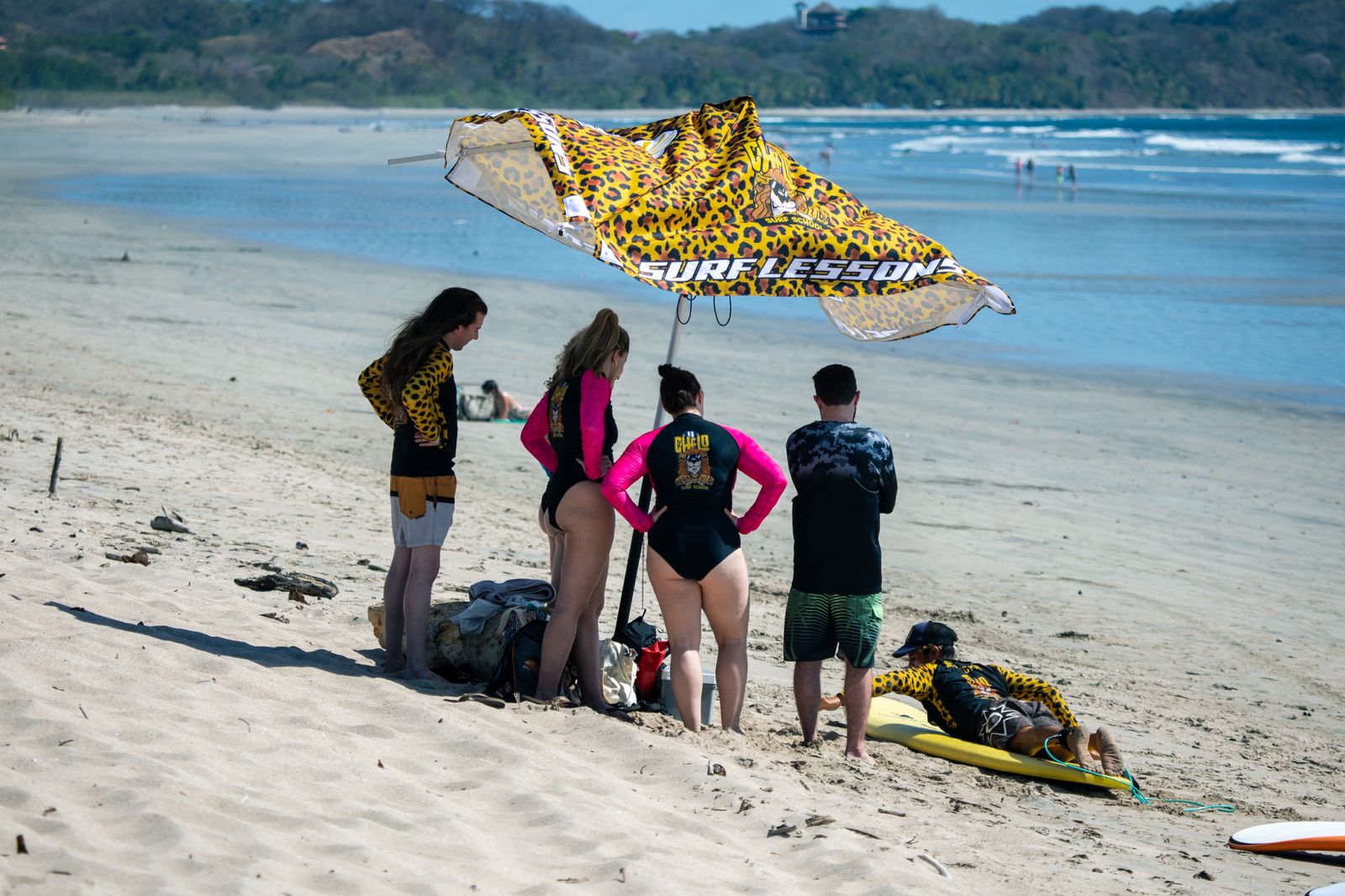 Chelo Surf School branded umbrella with students on the beach