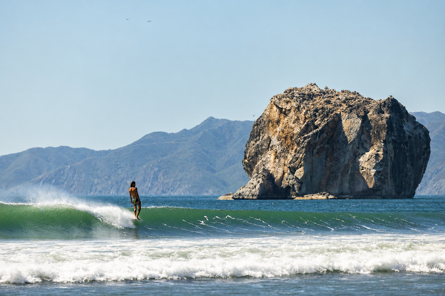 Surfer riding a wave at sunset in Nosara, Costa Rica